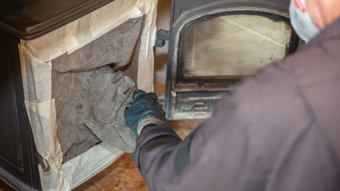 Un ramoneur utilise un équipement spécial pour nettoyer la cheminée d'un poêle à bois.