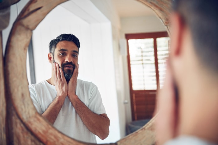 utilisations du beurre de cacahuète - homme barbu se regardant dans un miroir