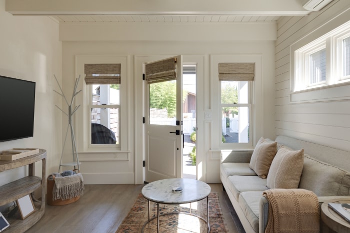 L'entrée principale et la salle familiale d'un cottage à Carlton, dans l'Oregon. La porte d'entrée est entrouverte, laissant entrer la lumière naturelle dans la pièce.