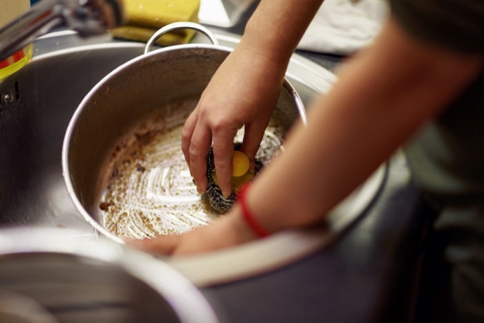 Personne frottant la casserole dans l'évier