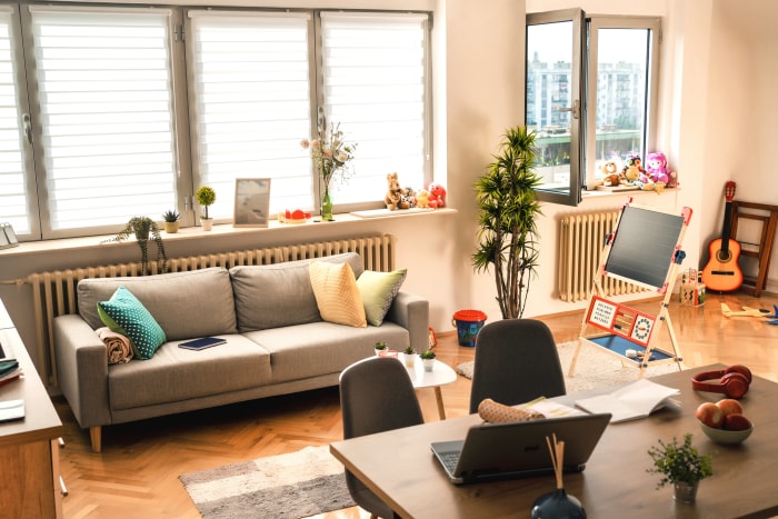 Un intérieur de salon avec parquet, de nombreuses fenêtres et une aire de jeux pour enfants sur le côté.