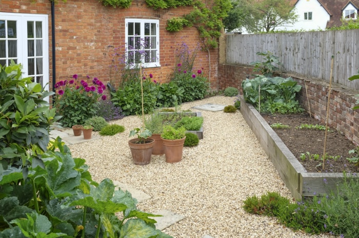 Une arrière-cour avec un jardin surélevé et du gravier utilisé pour l'aménagement paysager au lieu de l'herbe.