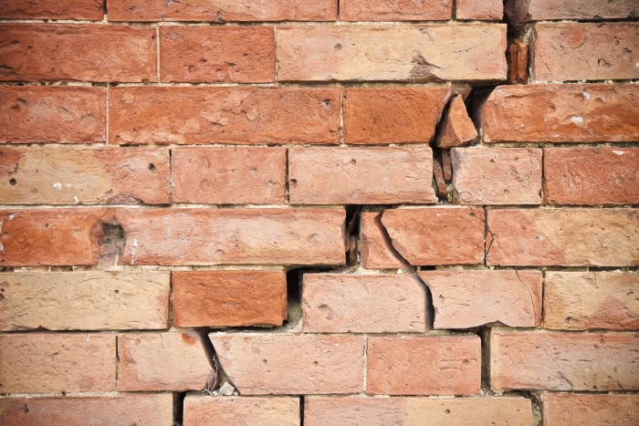 Fissure qui court en diagonale le long d'un mur ou d'une façade en briques.