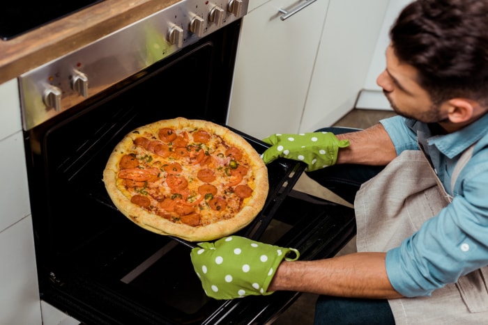 iStock-1070231674 gants de travail homme sortant une pizza du four avec des gants de cuisine