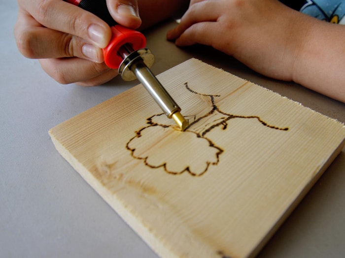 Personne utilisant l'outil de pyrogravure TRUArt Stage 1 pour dessiner un arbre sur du bois