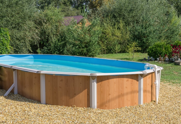 La piscine préfabriquée avec de l'eau thermale se trouve sur la pelouse près de la forêt. Journée ensoleillée