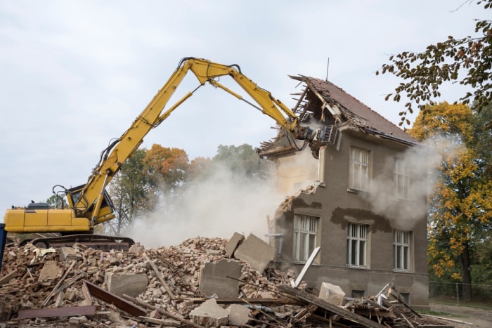 Grande pelleteuse démolissant une maison.