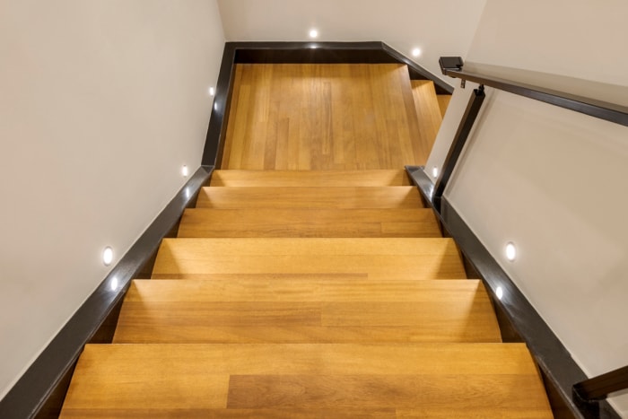 Escalier en bois dur qui tourne de 90 degrés vers la droite après un palier carré.