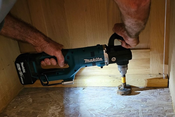 Une personne utilisant la lumière de la perceuse à angle droit Makita pour travailler dans un espace sombre