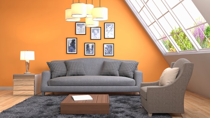 iStock-686988626 Idées de décoration murale pour le salon avec un mur d'accent orange et des œuvres d'art accrochées au mur