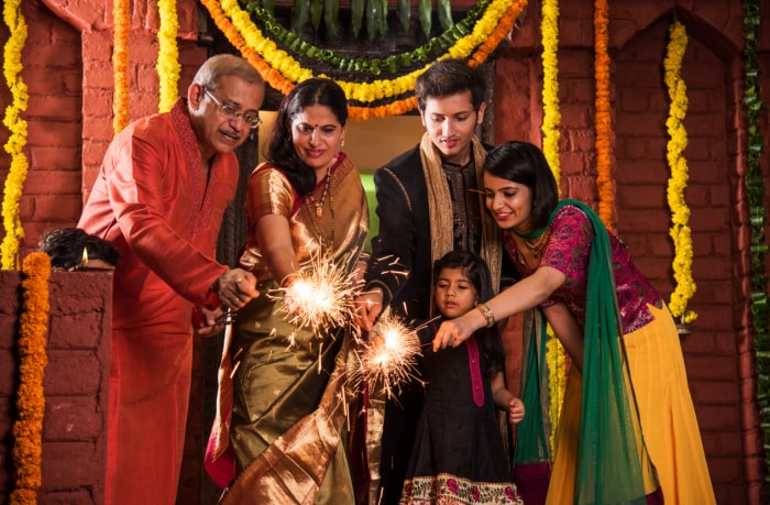 La famille tient ensemble les chandelles d'étincelles devant les décorations de Diwali et les guirlandes de marigold