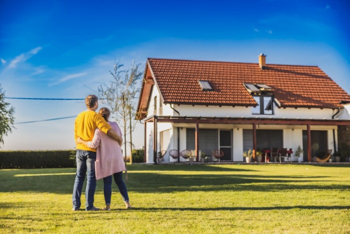 Un couple se fait un câlin en regardant leur nouvelle maison.