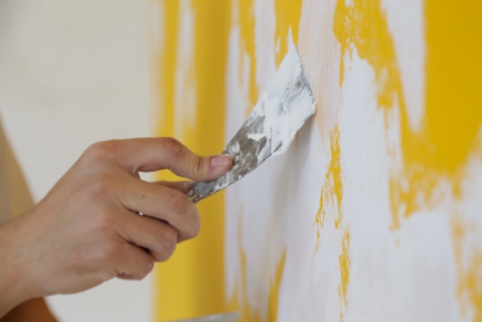 Personne appliquant une couche d'enduit sur un mur jaune