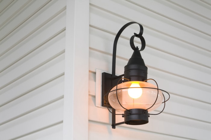 Lampe de porche à LED jaune vif montée sur le côté d'une maison.