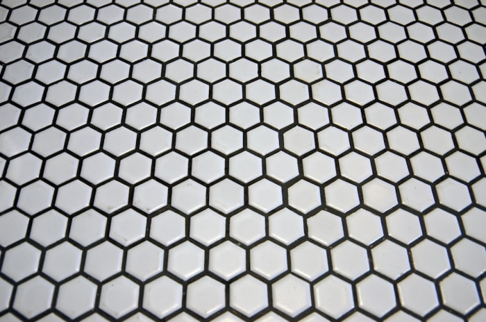 Carreaux hexagonaux blancs avec coulis foncé non sablé.