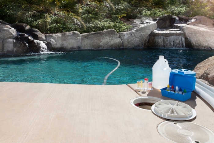 Les fournitures de nettoyage de piscine sont visibles devant une piscine.