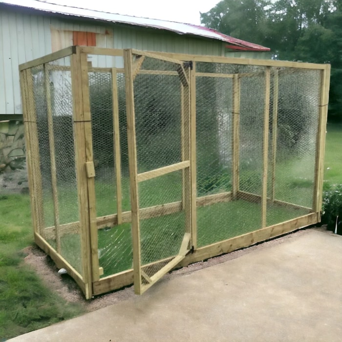 Une grande structure de boîte extérieure simple, adaptée aux poulets comme poulailler ou aux chats comme catio, se dresse dans une cour arrière rurale.