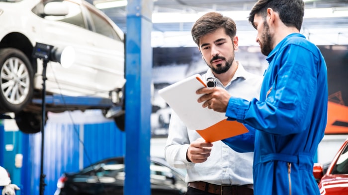 iStock-1256357961 problème avec un mécanicien de voitures électriques parlant à un client au centre de service