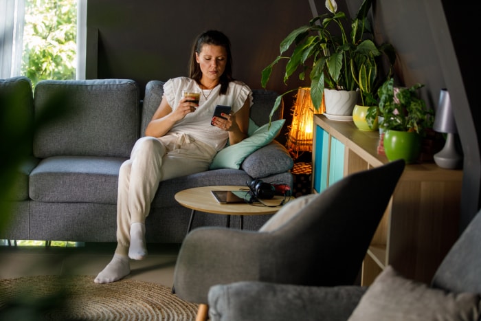 une femme sur un canapé se relaxant dans une atmosphère confortable en regardant son téléphone