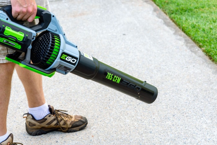 Une personne utilise le souffleur de feuilles Ego Power+ 765 CFM 56V pour éliminer les débris d'un trottoir.