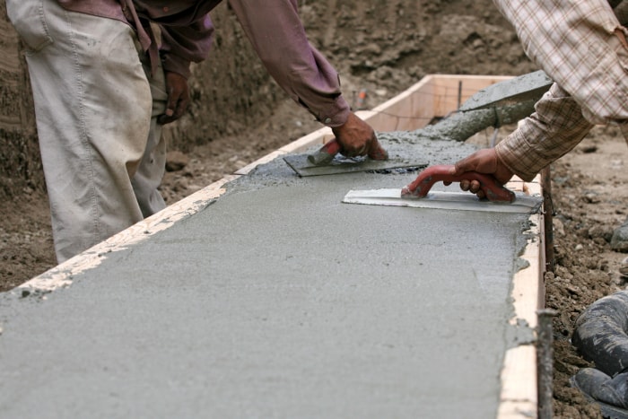 Des ouvriers de la construction répandent du béton mouillé.