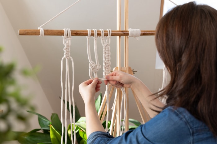 Une personne utilisant du macramé pour créer une tenture murale en fibre pour la maison.