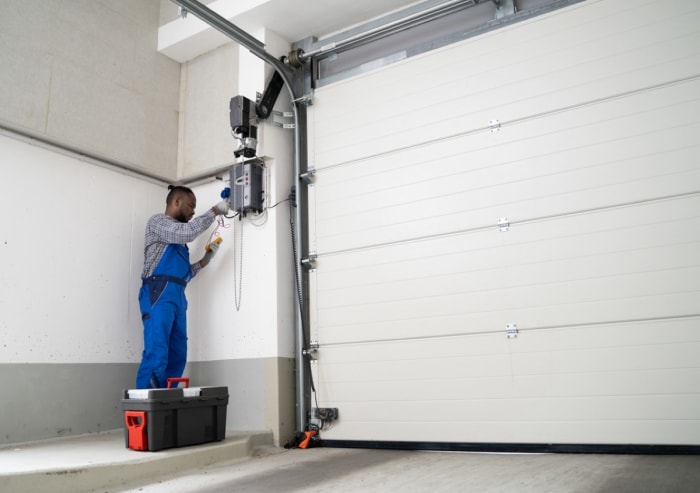 Un professionnel répare le ressort d'une porte de garage.