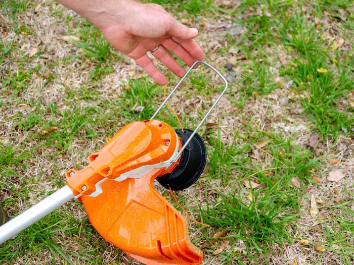 Main tenant la protection métallique d'un coupe-herbe Stihl