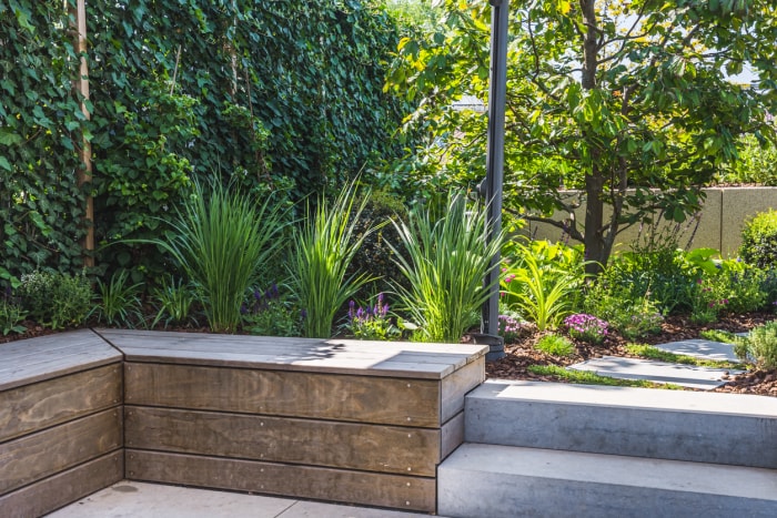 Banc de jardin en béton dans une cour avec aménagement paysager verdoyant.