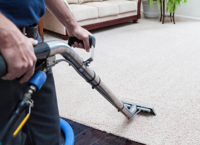 Gros plan sur un nettoyeur de tapis utilisé sur un tapis blanc. 