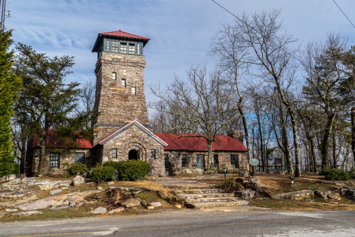 Un bâtiment en pierre avec une haute tour construite comme poste d'observation d'incendie avec un toit rouge et des fenêtres en grille de verre, une porte en arc rond, point culminant de l'État, Bunker Tower, Cheaha State Park, Alabama