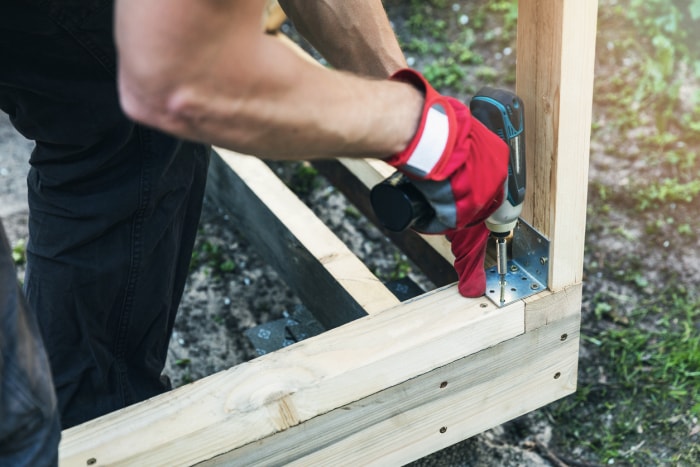 construction d'un hangar à bois - homme vissant un renfort d'angle