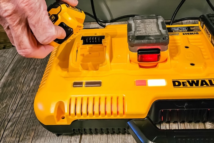 Une personne retirant une batterie chargée de la station de charge DeWalt.