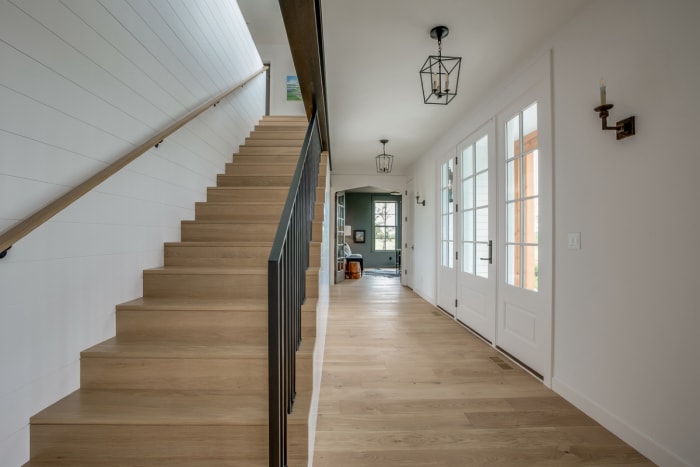 Une cage d'escalier droite menant au deuxième étage d'une maison moderne de style fermette.