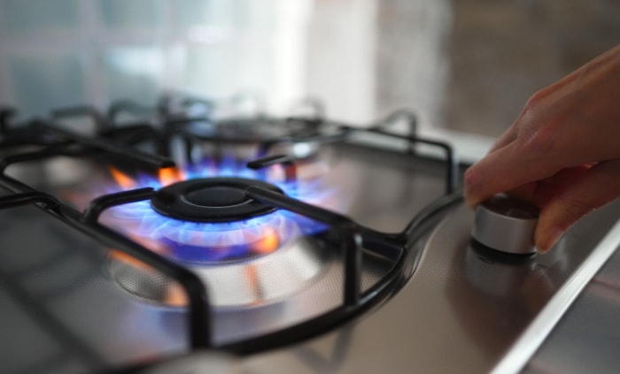 Femme allumant le brûleur à gaz de la cuisinière.