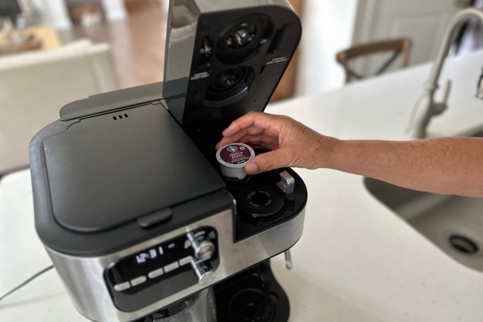 Une personne insérant une dosette de café dans la cafetière 4 en 1 Cuisinart Coffee Center Barista Bar