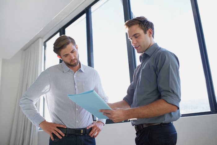 Deux hommes discutent autour d'un document bleu.