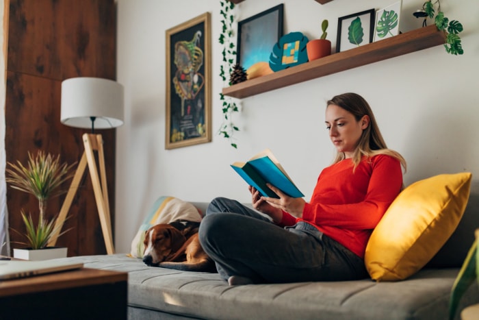 iStock-1324677620 comment améliorer votre vie femme lisant dans un coin douillet à la maison avec un chien