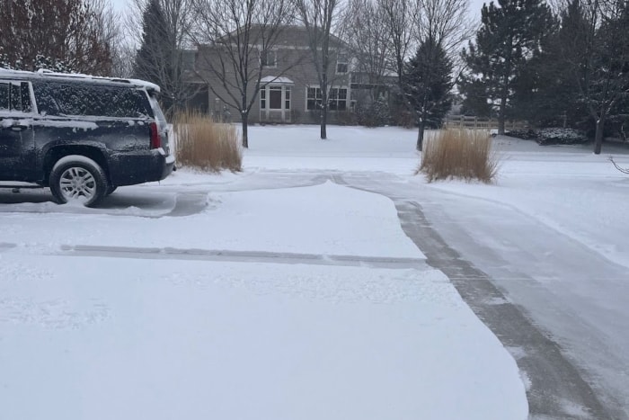 Une allée et un trottoir partiellement déneigés à l'aide de la souffleuse à neige légère Ego.