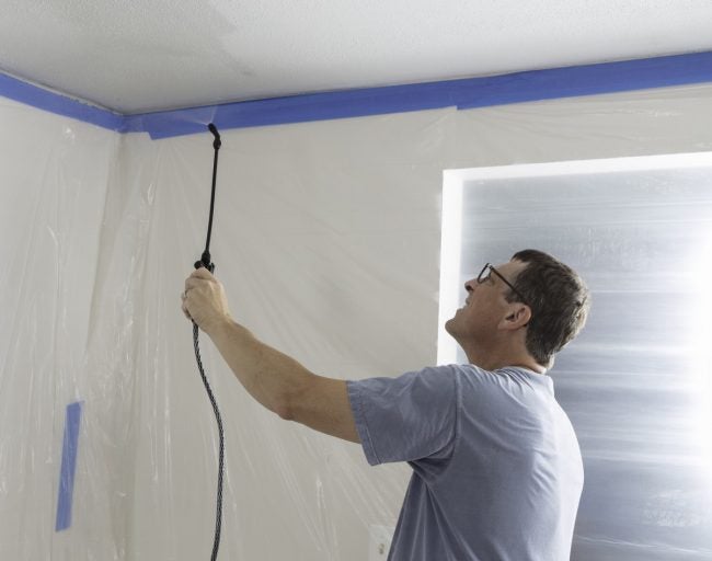 Un homme pulvérise du pulvérisant sur le plafond avant de l'enlever