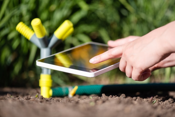 Un jardinier avec une tablette numérique utilisant un concept d'application de jardinage intelligent. Système d'arrosage.