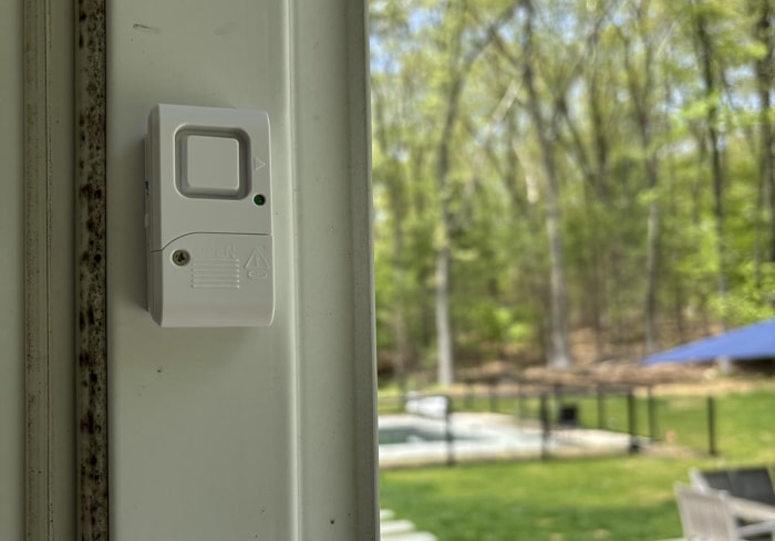 L'alarme sonore de fenêtre/porte GE installée sur une porte-fenêtre avec une piscine en arrière-plan.