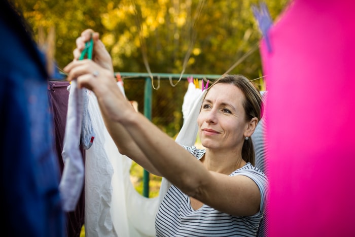 femme étend des vêtements sur une corde à linge à l'extérieur