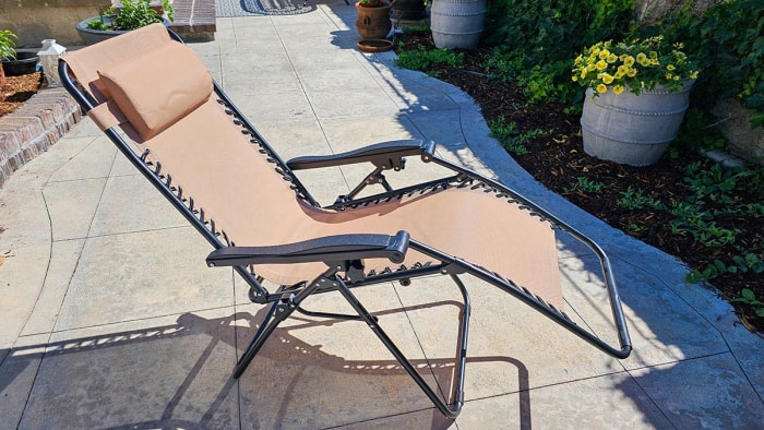 Chaise zéro gravité noire et beige inclinée sur une terrasse en béton