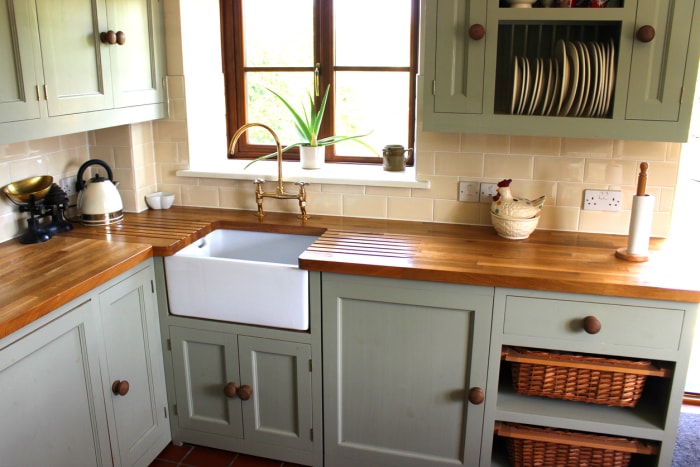 Cuisine moderne de style ferme avec comptoirs en blocs de boucher, armoires vertes et bleues et dosseret en carreaux de couleur crème