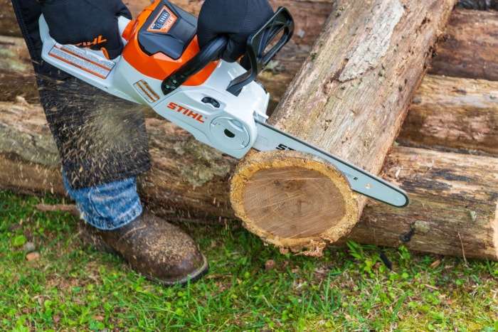 Une personne utilise la tronçonneuse électrique Stihl MSA pour scier l'extrémité d'une bûche