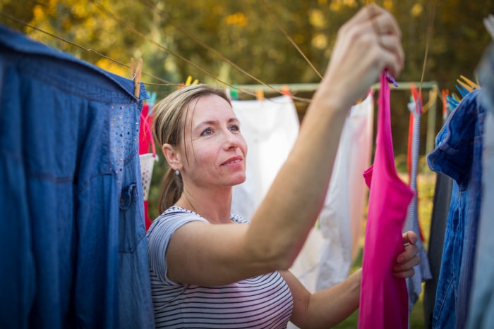 femme accrochant des vêtements de couleurs vives sur un fil à linge à l'extérieur