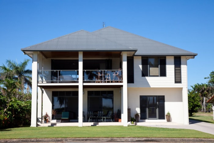 Une photo d'une maison blanche avec des volets noirs.