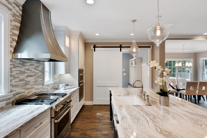 cuisine blanche et beige avec parquet et porte de grange coulissante blanche