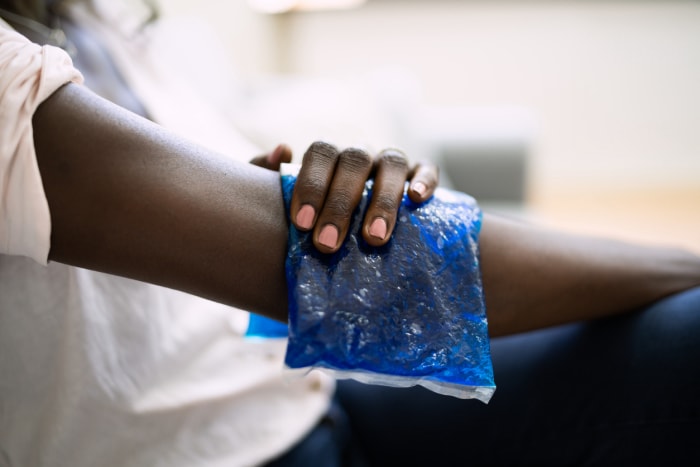 Une femme utilise une poche de gel glacé sur son bras blessé